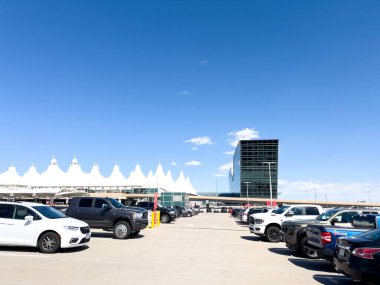 Denver, Colorado, ABD-15 Ağustos 2024 - Aydınlık bir günde Denver Uluslararası Havaalanı DIA 'nın otoparkının manzarası. Terminalin ikonik beyaz çadırlı çatısı ve cam yapısı...