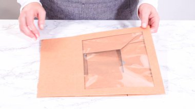 Elleri titizlikle bir kaseye taze kırmızı üzüm ekliyor, çeşitli peynirler, zeytinler ve pişirilmiş etlerle dolu güzel bir şarküteri kutusunu tamamlıyor.