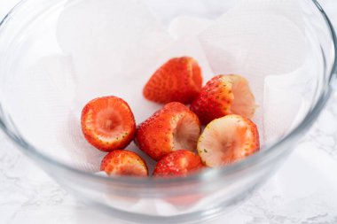 Taze yıkanmış ve kurutulmuş çilekler kağıt havluyla kaplı cam bir kasede dikkatlice düzenlenir. Atıştırmaya ya da daha fazla kullanılmaya hazır hale getirilir..