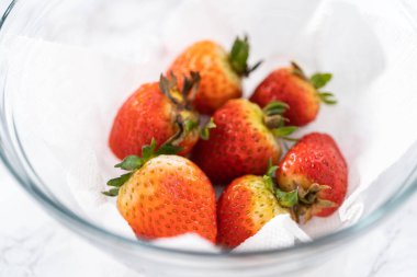 Taze yıkanmış ve kurutulmuş çilekler kağıt havluyla kaplı cam bir kasede dikkatlice düzenlenir. Atıştırmaya ya da daha fazla kullanılmaya hazır hale getirilir..