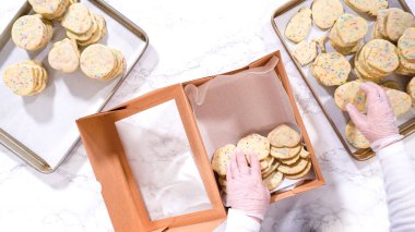 Düz yatıyordu. Kadın özenle, hamur karışımı şekerlemelerle dolu şekerli kurabiyeleri kırsal kahverengi bir karton kutuya yerleştiriyor..