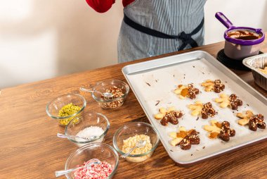 Çikolataya batırılmış ve fındık ezmesi ile süslenmiş kar tanesi şeklindeki kesme şekerli kurabiyeler yaratmak. Parşömen üzerinde zarif bir şekilde sunulmuş..