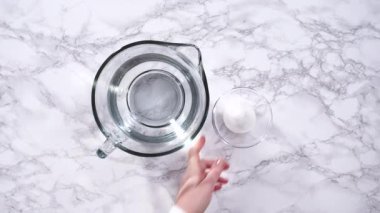 Cam ölçme bardakları suyla doludur, sıralanır ve dikkatli bir şekilde taze çilek yıkamada kullanılmaya hazırdır, kusursuz ve eksiksiz temizliği sağlar..