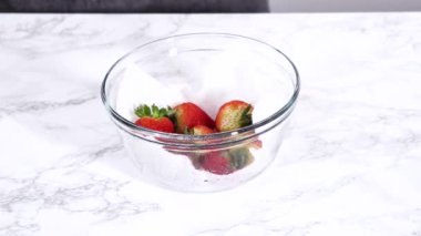 Çilekler, yeni yıkanmış ve kurutulmuş, cam bir kasede güzelce depolanmış kağıt havluyla kaplanmış ve tazeliği korumak için plastikle kaplanmış..