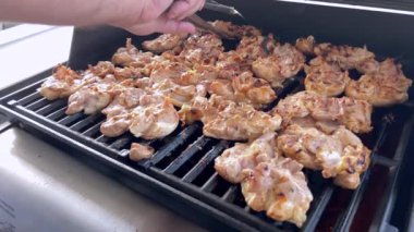 Salamura edilmiş tavuk butları küçük bir Weber ızgarasının ızgarasında cızırdar, havayı iştah açıcı bir koku ve hafif bir dumanla doldurur..