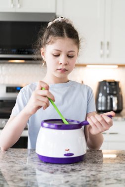 Odaklanmış bir dikkatle, bu filizlenen aşçılık sanatçısı krakerleri erimiş çikolataya batırarak iyi aydınlatılmış bir ev mutfağının sıcaklığında tatlı tatlar yaratıyor..