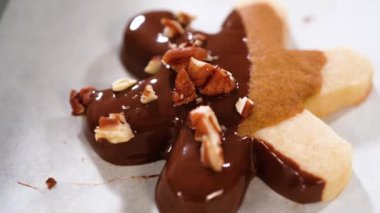 Çikolataya kısmen batırılmış ve fındık parçalarıyla kaplanmış, parşömen kağıdına yerleştirilmiş kesme şekerli kurabiyeler yaratmak..