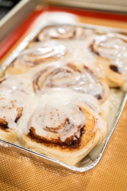 Fırından yeni çıkmış, tarçınlı çörek silikon bir hasırın üzerinde serinliyor, kremaları mutfak ışıklarının altında parlıyor..