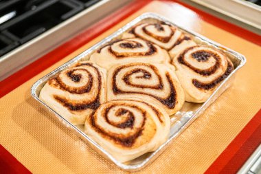 Fırından yeni çıkmış, tarçınlı çörek silikon bir hasırın üzerinde serinliyor, kremaları mutfak ışıklarının altında parlıyor..