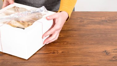 Tuzlu karamel şekerlemeleri ve zencefilli ekmek parçacıklarıyla süslenmiş zencefilli keki dikkatlice hediye etmek için açık pencereli beyaz bir kağıt bohça kek kutusuna yerleştiriyorum..