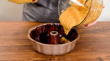 Pouring the gingerbread cake batter into the greased bundt cake pan, ready for a delightful caramel frosting. clipart