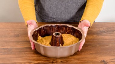 Pouring the gingerbread cake batter into the greased bundt cake pan, ready for a delightful caramel frosting. clipart