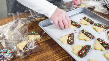 Dikkatlice paketlenmiş Noel kurabiyeleri, çikolataya batırılmış ve şeffaf selofan ambalajla sunulmuş, bayram hediyesi olarak mükemmel..