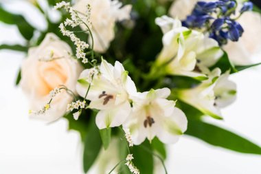 Taze beyaz güllerin ve çeşitli çiçeklerin bulunduğu büyüleyici bir buket, zarif bir vazoda düzenlenmiş, zamansız bir güzellik yayıyor..