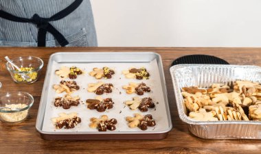 Çikolataya batırılmış ve fındık ezmesi ile süslenmiş kar tanesi şeklindeki kesme şekerli kurabiyeler yaratmak. Parşömen üzerinde zarif bir şekilde sunulmuş..