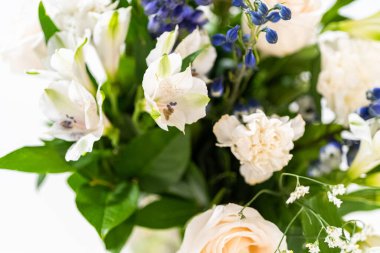 Taze beyaz güllerin ve çeşitli çiçeklerin bulunduğu büyüleyici bir buket, zarif bir vazoda düzenlenmiş, zamansız bir güzellik yayıyor..