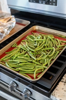 Watch as fresh green beans are beautifully roasted to perfection on a baking sheet with a silicone mat, adding a burst of flavor to your meal. clipart