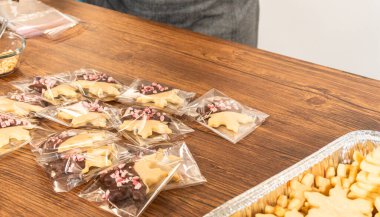 Dikkatlice paketlenmiş Noel kurabiyeleri, çikolataya batırılmış ve şeffaf selofan ambalajla sunulmuş, bayram hediyesi olarak mükemmel..