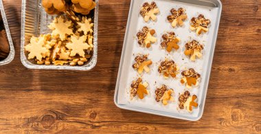 Zencefilli adam kurabiyeleri, çikolata soslu ayaklar, bol bol kızarmış hindistan cevizi talaşı serpiştirilmiş, parşömen kağıdına ustalıkla yerleştirilmiş..