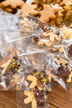 Dikkatlice paketlenmiş Noel kurabiyeleri, çikolataya batırılmış ve şeffaf selofan ambalajla sunulmuş, bayram hediyesi olarak mükemmel..