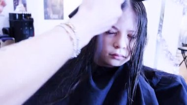 Nazik eller saç kurutma makinesini yeni kesilmiş genç bir kızın üzerinden geçirir ve titiz bir şekilde kestikten sonra kurutma işlemini gösterir. Kurutucunun sıcaklığı onun kilitlerine hayat veriyor.