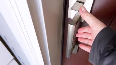 Bir kişinin eli, fırçalanmış metal bir kapı kulpu kullanılarak bir odaya girme ya da çıkma eylemini gösteren bir kapı açma işlemi sırasında yakalanır..