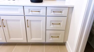 Bu ana banyoda geniş beyaz dolaplar var. Parlak altın kulplarla tamamlanmış, zarif gri zemin üzerine kurulmuş modern ve rafine edilmiş bir alan yaratıyor..