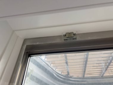 Bodrum penceresinin yakın plan görüntüsü beyaz iç pencere çerçevesini gösteriyor. Metal bir pencerenin dış görünüşü ise küçük taşlarla kaplı. Temiz pencere çerçevesi ve iyi korunmuş çerçeve