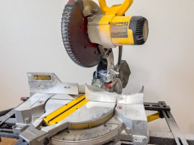 Yüzeyinde talaş olan bir miter testeresinin detaylı bir görüntüsü bir ev yenileme projesinde kullanıldığını gösteriyor. Bıçak ve ölçü kılavuzu kesim için açıkça görülebilir..