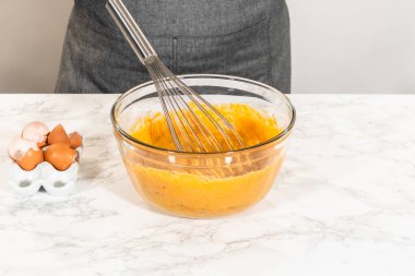 Sıcak bir mutfakta, büyük bir karıştırma kabı malzemelerin ustalıkla harmanlanması için sahne olur, kek karışımından nefis bir ev yapımı balkabağı pastası hazırlamak için sahne hazırlar.