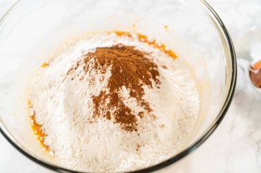 Ağız sulandırıcı ev yapımı balkabağı pastası için büyük bir karıştırma kabında ustalıkla harmanlanmış malzemelerin yakın çekimi..