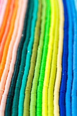 Beyaz bir masadaki renklere göre düzenlenmiş canlı bir kil boncuk koleksiyonu genç zanaatkarlara kendi eşsiz bileziklerini yapmaları için ilham vermeye hazır..