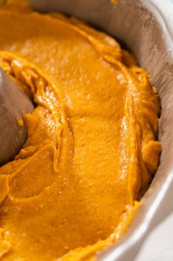 Pasta hamurunu kek tepsisine dökerek nefis bir ev yapımı balkabağı pastası yapmaya hazır..