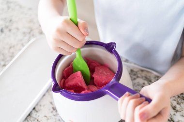 Hevesli gözler canlı çömleğe odaklanmış, eriten şekerler genç bir aşçı karışımı nazikçe kıvırıyor, sade atıştırmalıkları lezzetli yiyeceklere dönüştürmeye hazırlanıyor..