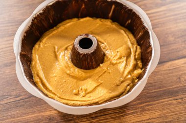 Pouring the gingerbread cake batter into the greased bundt cake pan, ready for a delightful caramel frosting. clipart