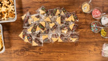 Dikkatlice paketlenmiş Noel kurabiyeleri, çikolataya batırılmış ve şeffaf selofan ambalajla sunulmuş, bayram hediyesi olarak mükemmel..