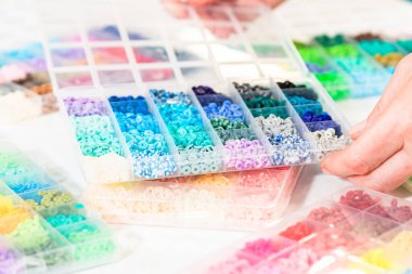 Beyaz bir masaya yerleştirilmiş çeşitli kil boncuk kutuları yaratıcı çocukların el sanatları projesini bekliyor..