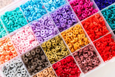 Beyaz bir masaya yerleştirilmiş çeşitli kil boncuk kutuları yaratıcı çocukların el sanatları projesini bekliyor..