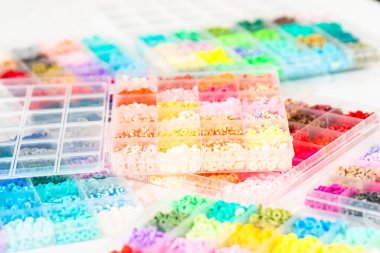 Beyaz bir masaya yerleştirilmiş çeşitli kil boncuk kutuları yaratıcı çocukların el sanatları projesini bekliyor..