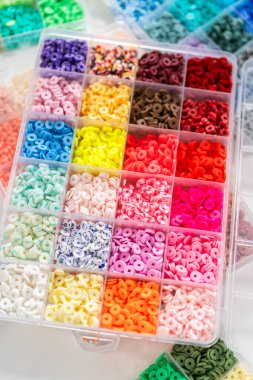 Beyaz bir masaya yerleştirilmiş çeşitli kil boncuk kutuları yaratıcı çocukların el sanatları projesini bekliyor..
