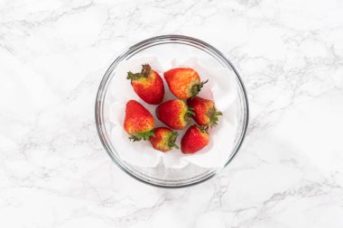 Taze yıkanmış ve kurutulmuş çilekler kağıt havluyla kaplı cam bir kasede dikkatlice düzenlenir. Atıştırmaya ya da daha fazla kullanılmaya hazır hale getirilir..