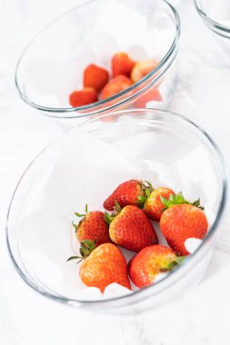 Taze yıkanmış ve kurutulmuş çilekler kağıt havluyla kaplı cam bir kasede dikkatlice düzenlenir. Atıştırmaya ya da daha fazla kullanılmaya hazır hale getirilir..