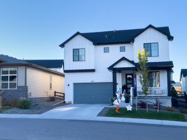 Castle Rock, Colorado, ABD-27 Ekim 2024 modern iki katlı bir banliyö evi, beyaz dış ve siyah aksanlı, verandalı, bağlı garajlı ve garaj yolu olan. Ev dekore edildi.