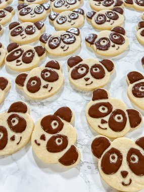 A playful assortment of panda face sugar cookies decorated with chocolate icing, forming adorable expressions. Each cookie has chocolate details for the panda eyes, nose, and ears, creating a clipart