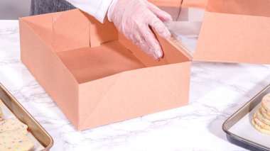 Hamurun içine şeker parçacıkları doldurulmuş olan kurabiyeler, özenle özenle hazırlanmış, kırsal kahverengi bir karton kutuya konur..