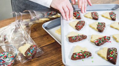 Dikkatlice paketlenmiş Noel kurabiyeleri, çikolataya batırılmış ve şeffaf selofan ambalajla sunulmuş, bayram hediyesi olarak mükemmel..