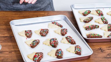 Dikkatlice paketlenmiş Noel kurabiyeleri, çikolataya batırılmış ve şeffaf selofan ambalajla sunulmuş, bayram hediyesi olarak mükemmel..