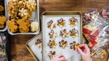 Düz yatıyordu. Dikkatlice paketlenmiş Noel kurabiyeleri, çikolataya batırılmış, ezilmiş fındık serpiştirilmiş, ve şeffaf selofan ambalajla sunulmuş..