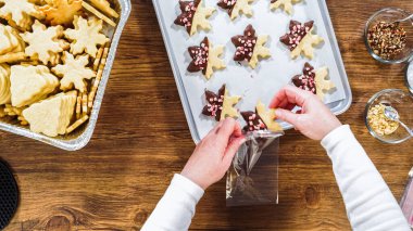 Düz yatıyordu. Dikkatlice paketlenmiş Noel kurabiyeleri, çikolataya batırılmış, ezilmiş fındık serpiştirilmiş, ve şeffaf selofan ambalajla sunulmuş..