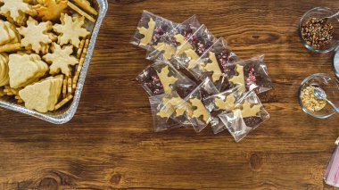 Düz yatıyordu. Dikkatlice paketlenmiş Noel kurabiyeleri, çikolataya batırılmış, ezilmiş fındık serpiştirilmiş, ve şeffaf selofan ambalajla sunulmuş..